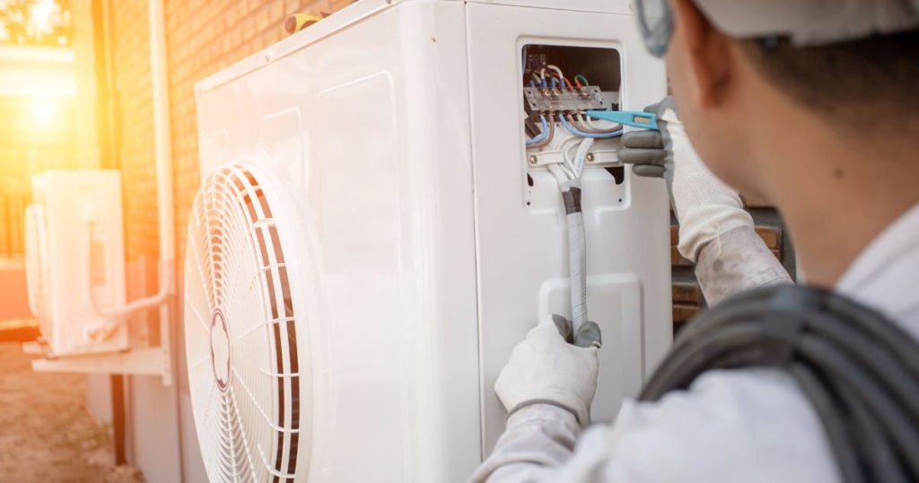 Een vakman installeert een warmtepomp die buiten is geplaatst