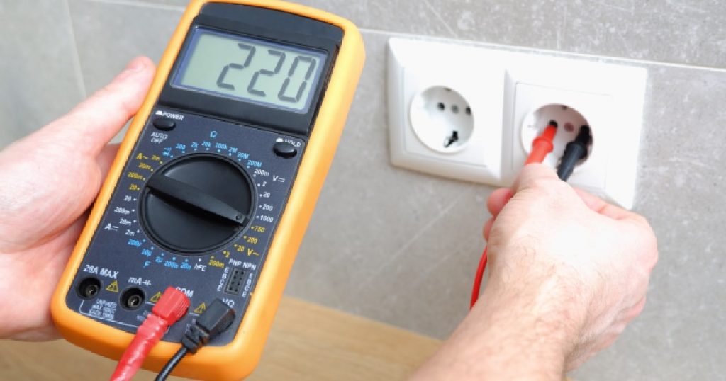 Een man gebruikt een voltmeter om de spanning op het elektriciteitsnet te meten.